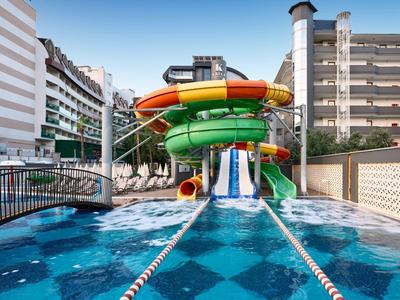 Wasserpark mit bunten Wasserrutschen und Schwimmbecken zwischen Hotelgebäuden.