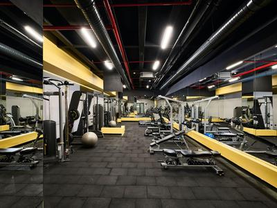 Moderní posilovna se zařízeními, zrcadlovými stěnami a černou podlahou.