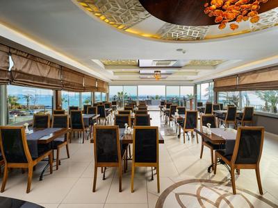 Helles Restaurant mit Holzmöbeln und großen Fenstern mit Meerblick.