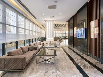 Heller, moderner Hotel-Lobby-Bereich mit Sofa, Glastisch und großen Fenstern.