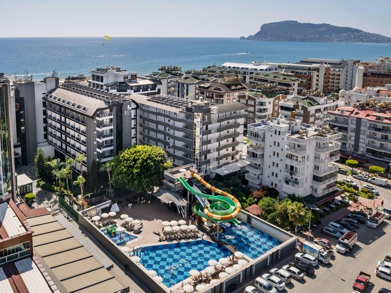 Stadtansicht mit Wohngebäuden, Pool und Rutsche, dahinter das Meer und eine Insel.