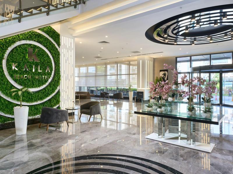 Moderner Hotel-Lobby-Bereich mit grüner Wanddekoration und glänzendem Marmorboden.