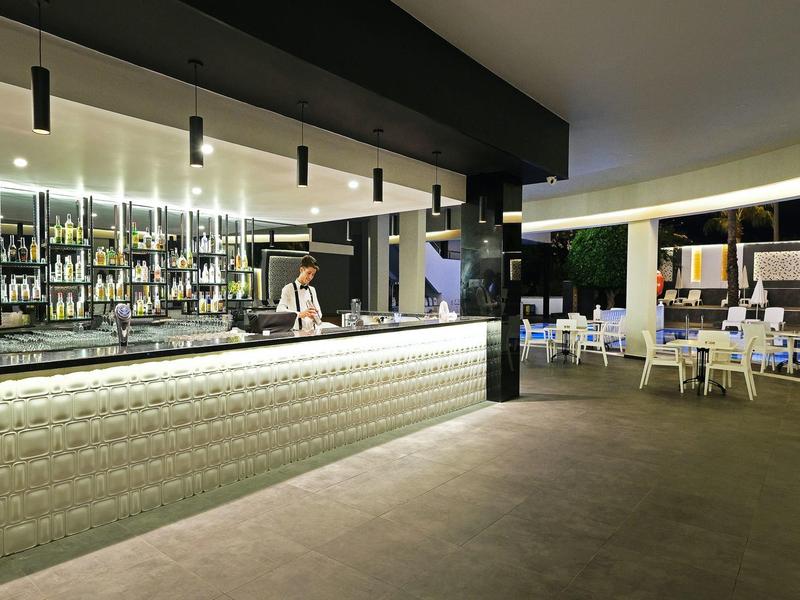 Moderner Hotelbarbereich mit beleuchtetem Tresen und Sitzgelegenheiten im offenen Raum.