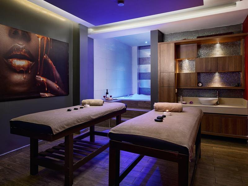 Gemütlicher Spa-Raum mit zwei Massageliegen, stimmungsvoller Beleuchtung und beruhigender Dekoration.