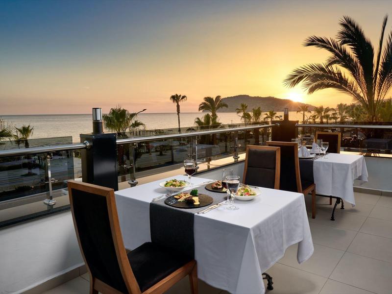 Terrasse mit gedeckten Tischen und Meerblick bei Sonnenuntergang