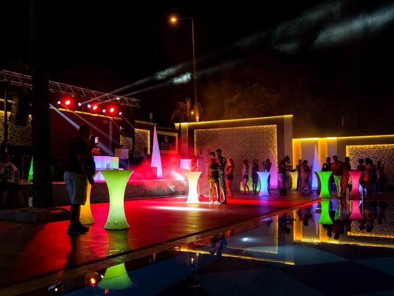 Nächtliche Poolparty mit bunten Lichtern und Tanzenden an einem Hotel