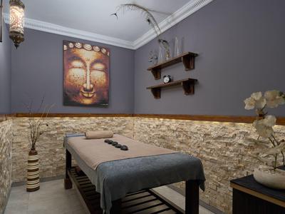 Cozy massage room with stone wall, Buddha painting, and relaxing lighting.