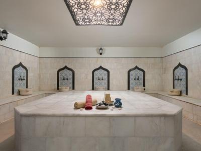 A luxurious marble hammam with five mirrors and decorative ceiling lighting.