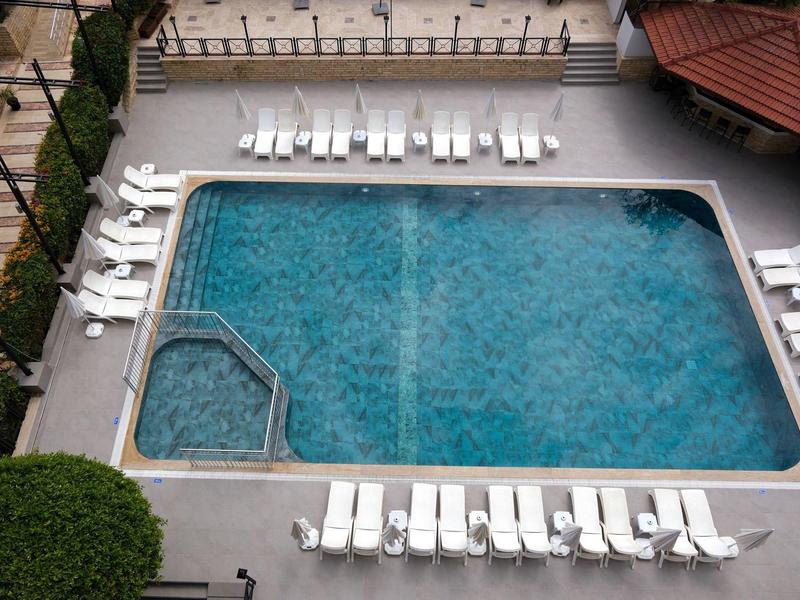 Rectangular outdoor pool with clear blue water surrounded by white lounge chairs.