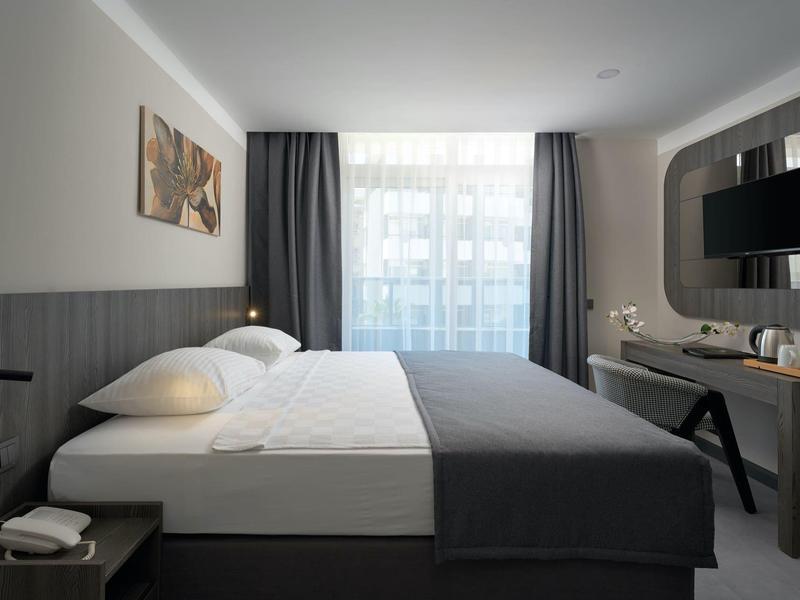 Modern hotel room with large bed and window with curtains.