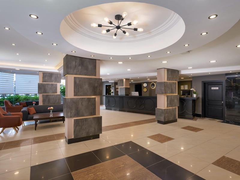 Bright hotel lobby area with upholstered chairs and modern reception desk.