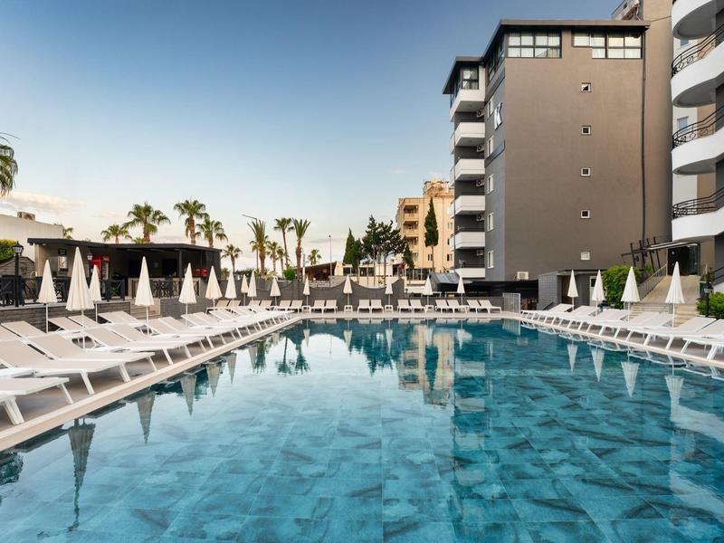 Modern outdoor pool with lounge chairs and umbrellas in a hotel complex.