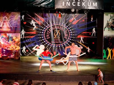 Zwei Tänzer in farbenfrohen Kostümen treten auf einer Bühne mit lebhaftem Hintergrund auf.