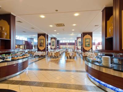 Spacious buffet area in a hotel dining room with various food stations and seating in the background.