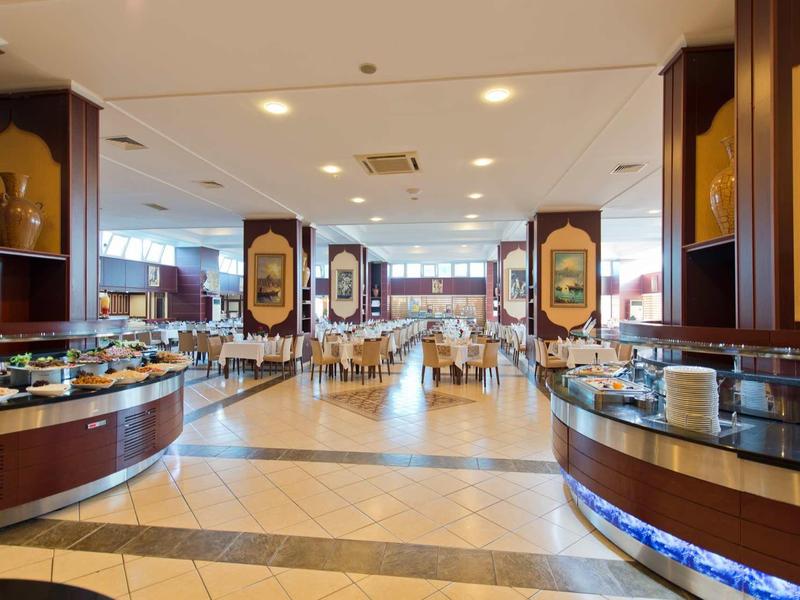 Spacious buffet area in a hotel dining room with various food stations and seating in the background.
