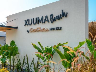 Muro esterno con insegna dell'hotel XUUMA Beach sotto un cielo sereno.
