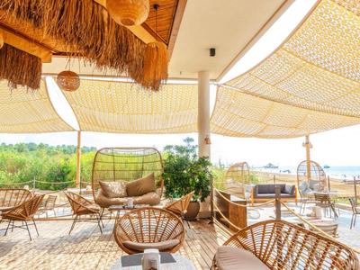 Accogliente terrazza con sedie in vimini, pavimento in legno e vista sul paesaggio verde.