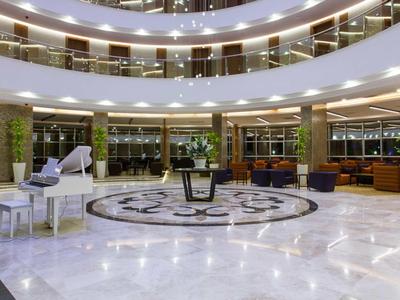 Spacieuse hall d'hôtel avec piano blanc et espaces de sièges modernes.