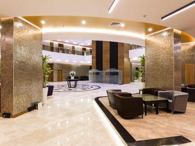 Hall d'hôtel moderne avec des espaces de détente confortables et un sol en marbre clair.