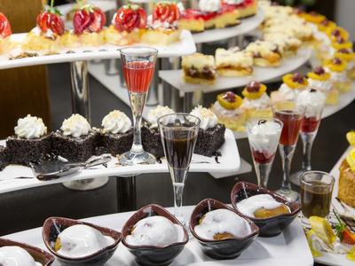 Buffet avec une sélection de desserts et de boissons dans des verres sur des plateaux blancs.