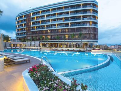 Hôtel moderne avec grande piscine extérieure et transats sous un ciel nuageux