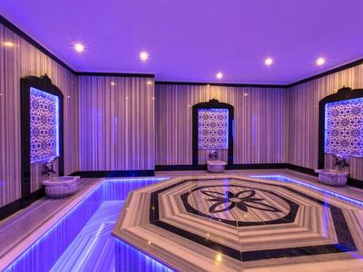 Intérieur d'un bain turc avec marbre illuminé et fontaines décoratives.