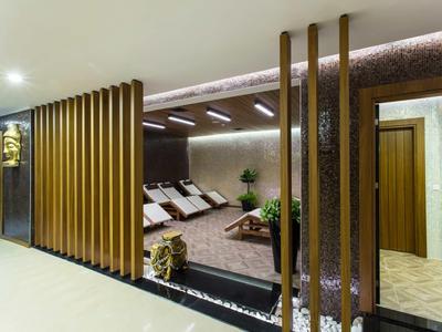 Moderní wellness sezení s lehátky, dřevěnými panely a teplým osvětlením.