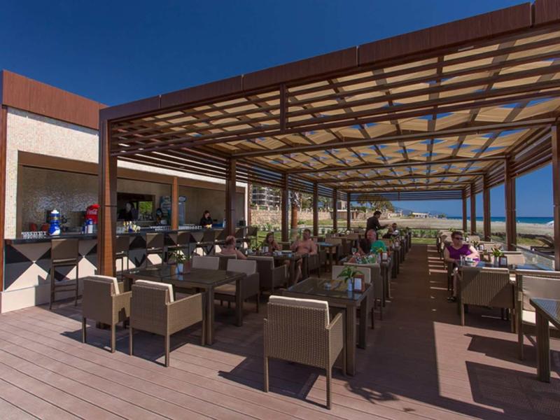 Terrasse ouverte avec tables et chaises offrant une vue sur la mer sous un ciel clair.