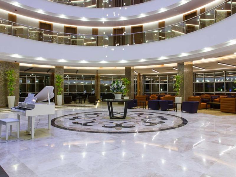 Spacieuse hall d'hôtel avec piano blanc et espaces de sièges modernes.