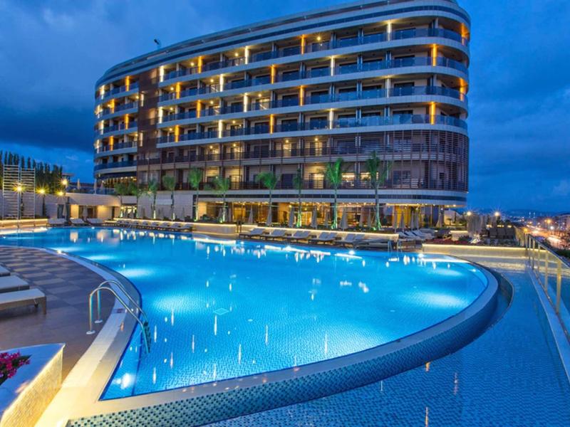 Hôtel moderne avec piscine extérieure éclairée au crépuscule.