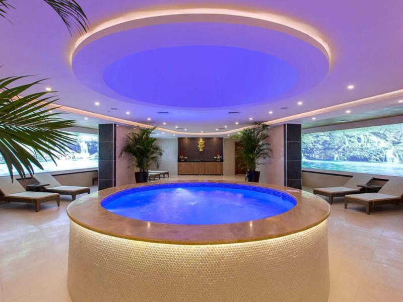 Bain à remous rond dans un spa de luxe avec éclairage bleu au plafond et chaises longues