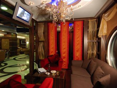 Cozy hotel lounge with comfortable sofas, red curtains, and chandelier.