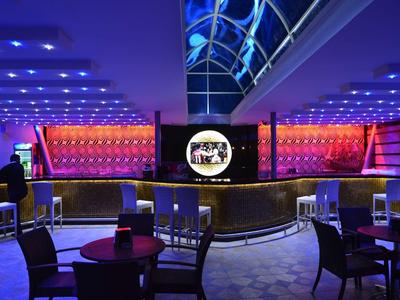 Modern hotel bar with colorful LED lighting and stylish seating areas.