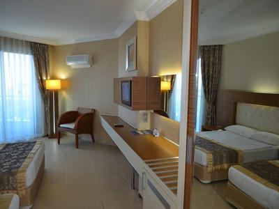 Bright hotel room with double bed, desk, chair, and large mirror.
