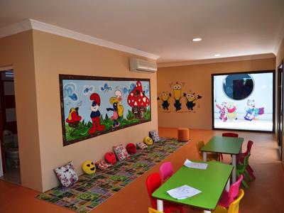 Colorful children's playroom with small tables, chairs, and cartoon-themed wall decorations.