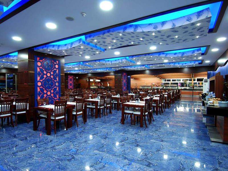 Spacious modern hotel dining area with blue lighting and marble tile floor.