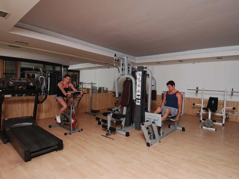 Gym room with exercise machines and two people working out.