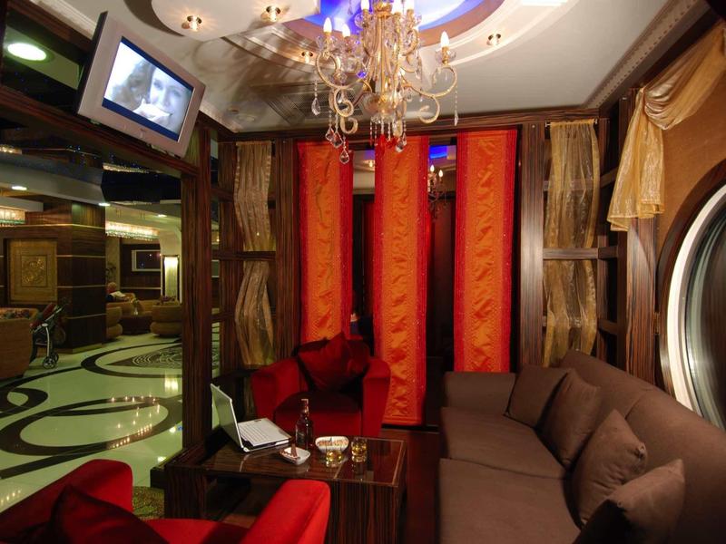 Cozy hotel lounge with comfortable sofas, red curtains, and chandelier.