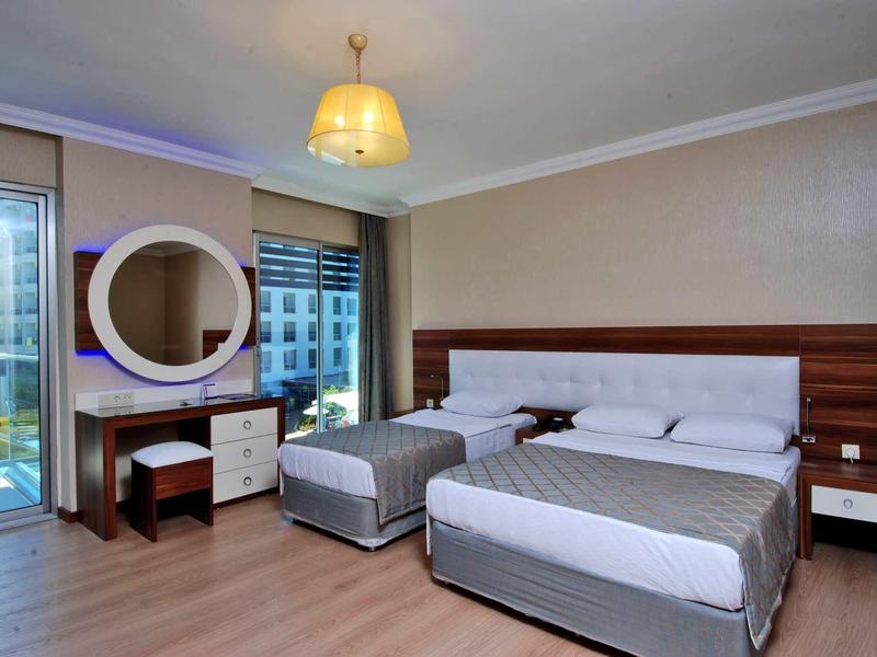 Modern hotel room with two beds, vanity table, and large window overlooking the city.