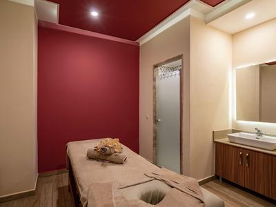 Gezellige spa kamer met massagetafel, handdoeken en wastafel in warme kleuren.