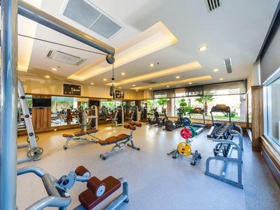 Heller Fitnessraum mit Gewichten, Geräten, Spiegeln und großen Fenstern in moderner Ausstattung.