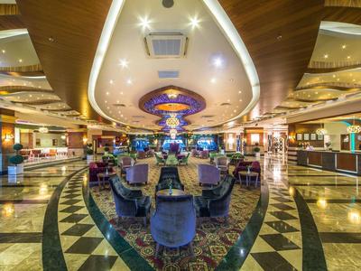 Großer, luxuriöser Hotellobby mit Polstersesseln, glänzendem Marmorfußboden und dekorativem Deckenlicht.