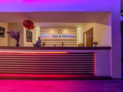Moderne hotelreceptie met verlicht Spa & Wellness-bord en decoratieve balie.