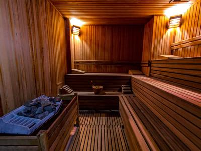 Houtsauna met meerlaagse banken en saunakachel, warme verlichting zorgt voor een ontspannen sfeer.
