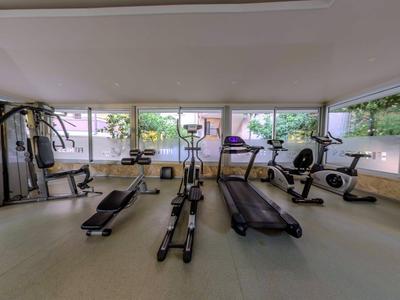Lichte fitnessruimte met trainingsapparatuur en grote ramen met uitzicht op groen.