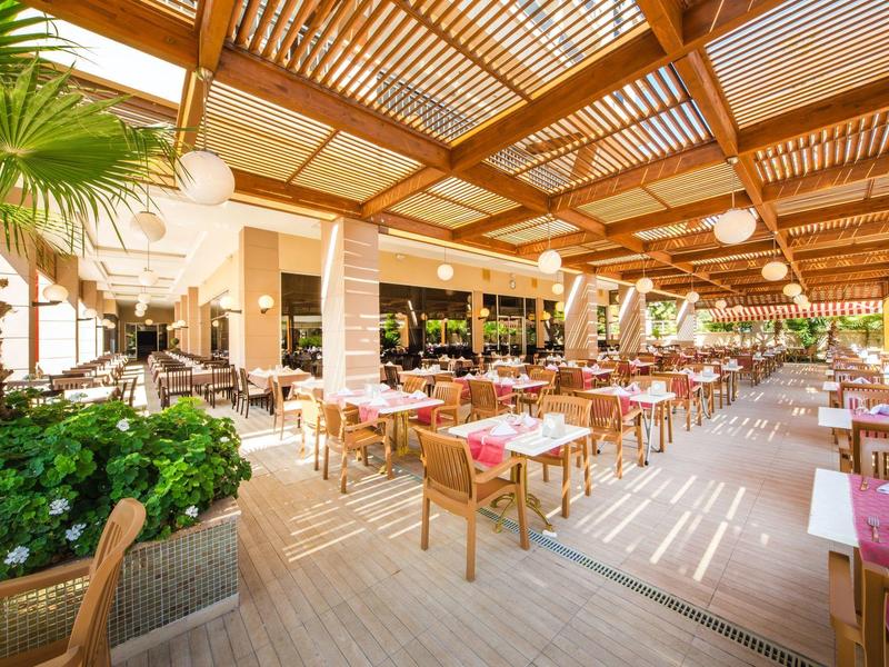 Spacious outdoor restaurant seating under a wooden pergola with natural light.