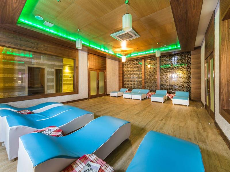 Relaxing spa room with blue lounge chairs, wooden walls, and green ceiling lights.