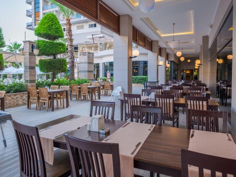 Outdoor restaurant seating with wooden tables and chairs under a modern covered patio.