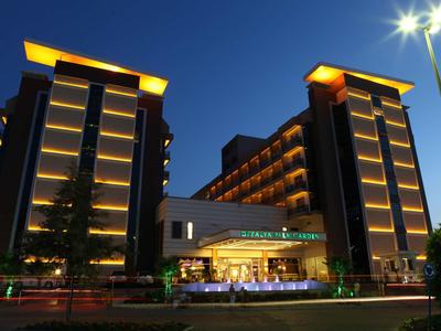 Moderní hotel osvětlený v noci se dvěma věžemi a středním vchodem.