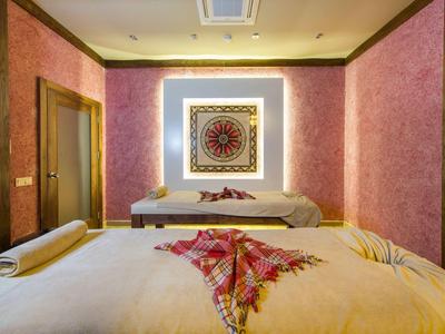 Gemütlicher Wellnessraum mit zwei Massageliegen, rosa Wänden und dekorativem Wandbild.
